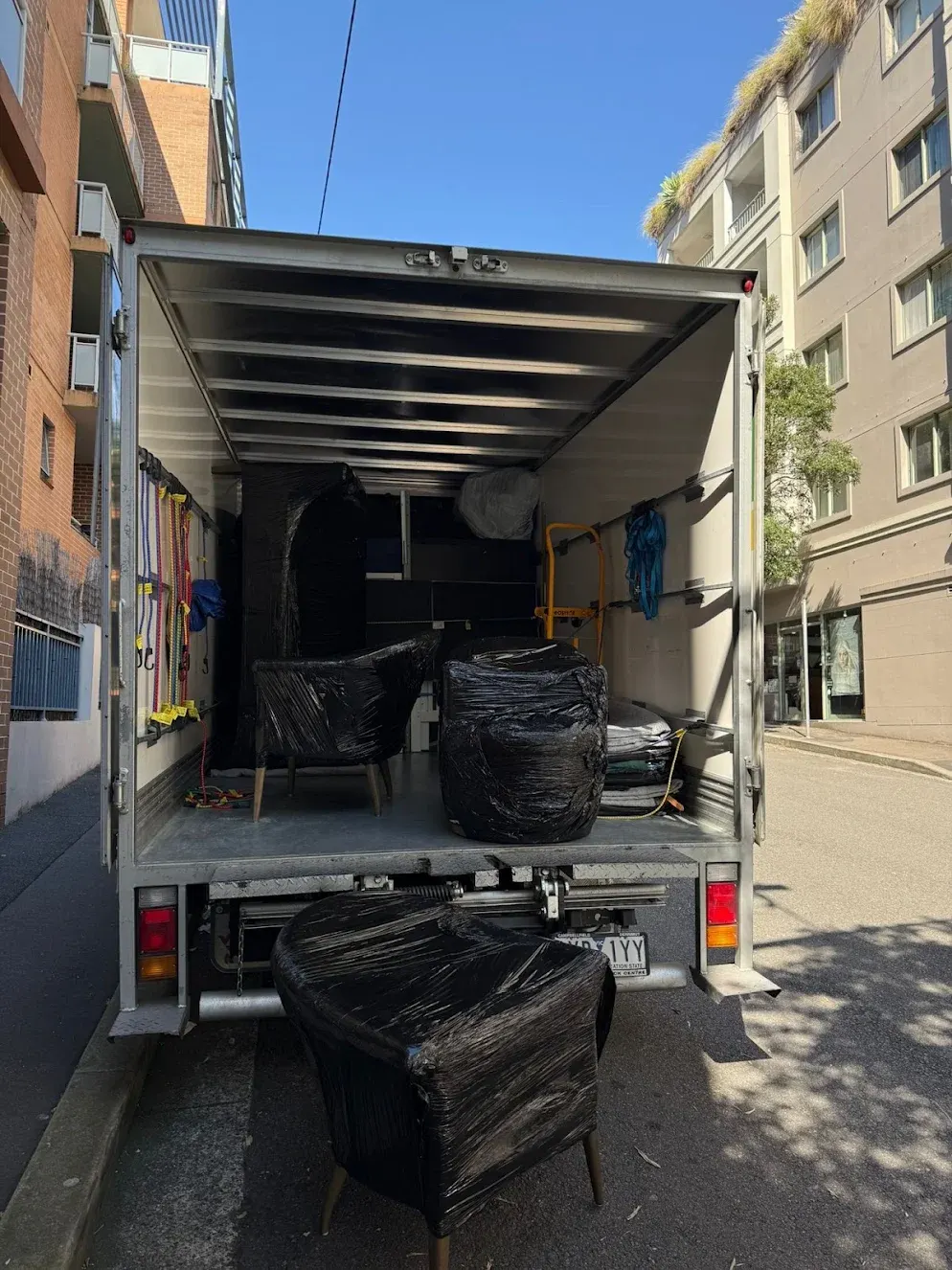 Office furniture wrapped and secured for transport in a Conquer Removals truck